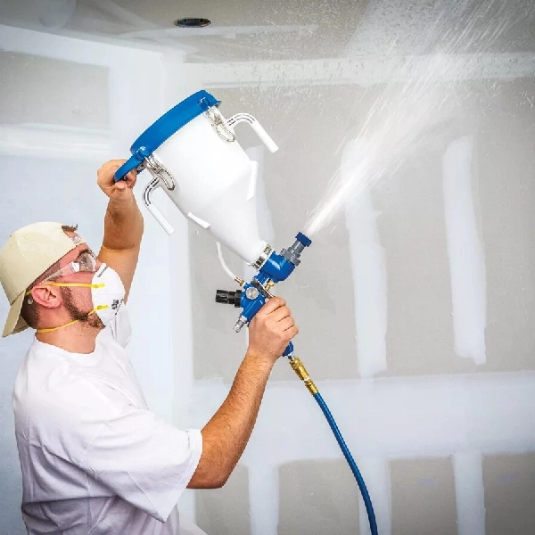 A man applying a white color paint with spray in Dubai